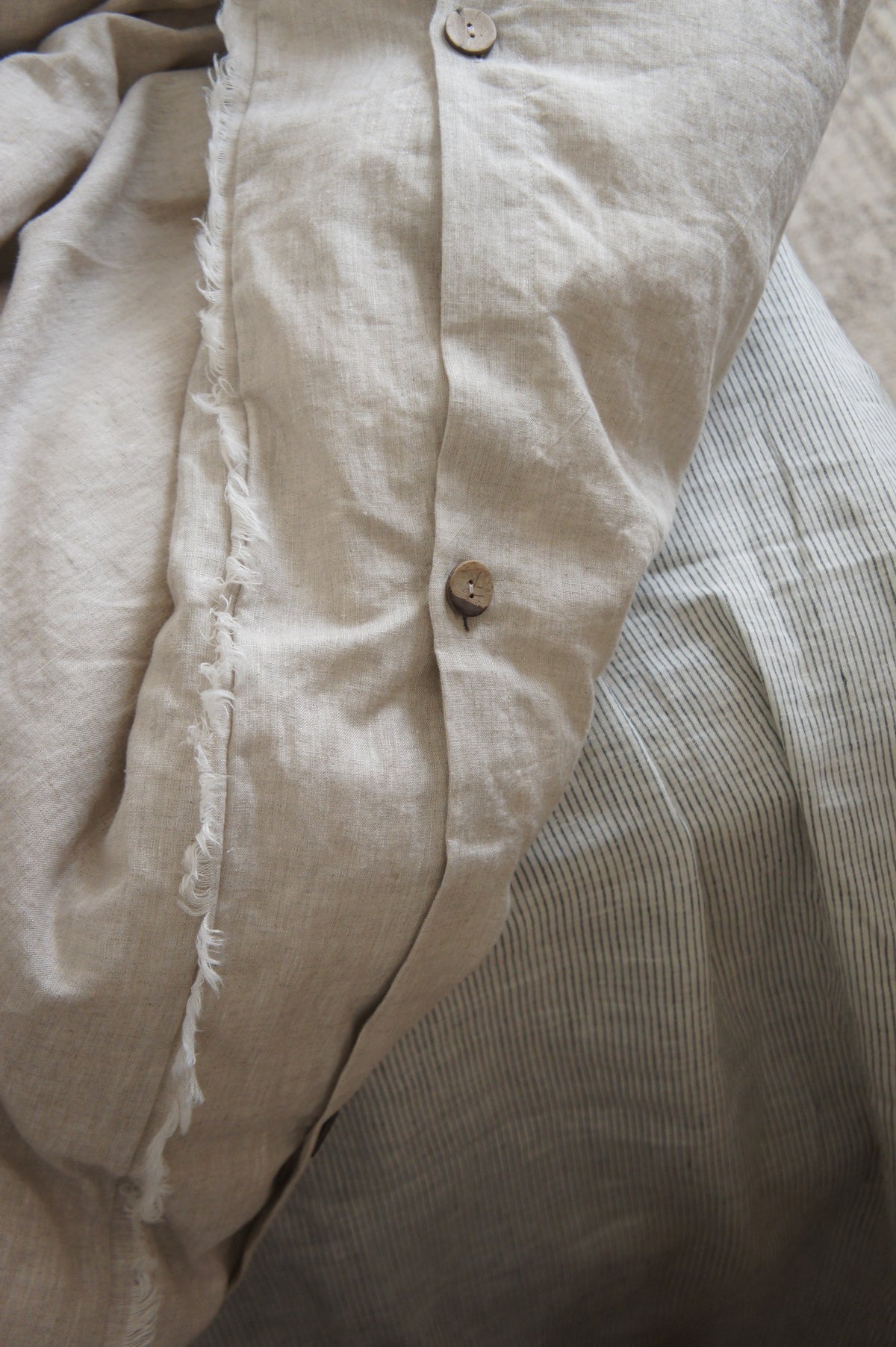 SOL Linen Sable frayed linen duvet cover displayed on a bed in a cozy bedroom setting, showcasing its soft, textured fabric.