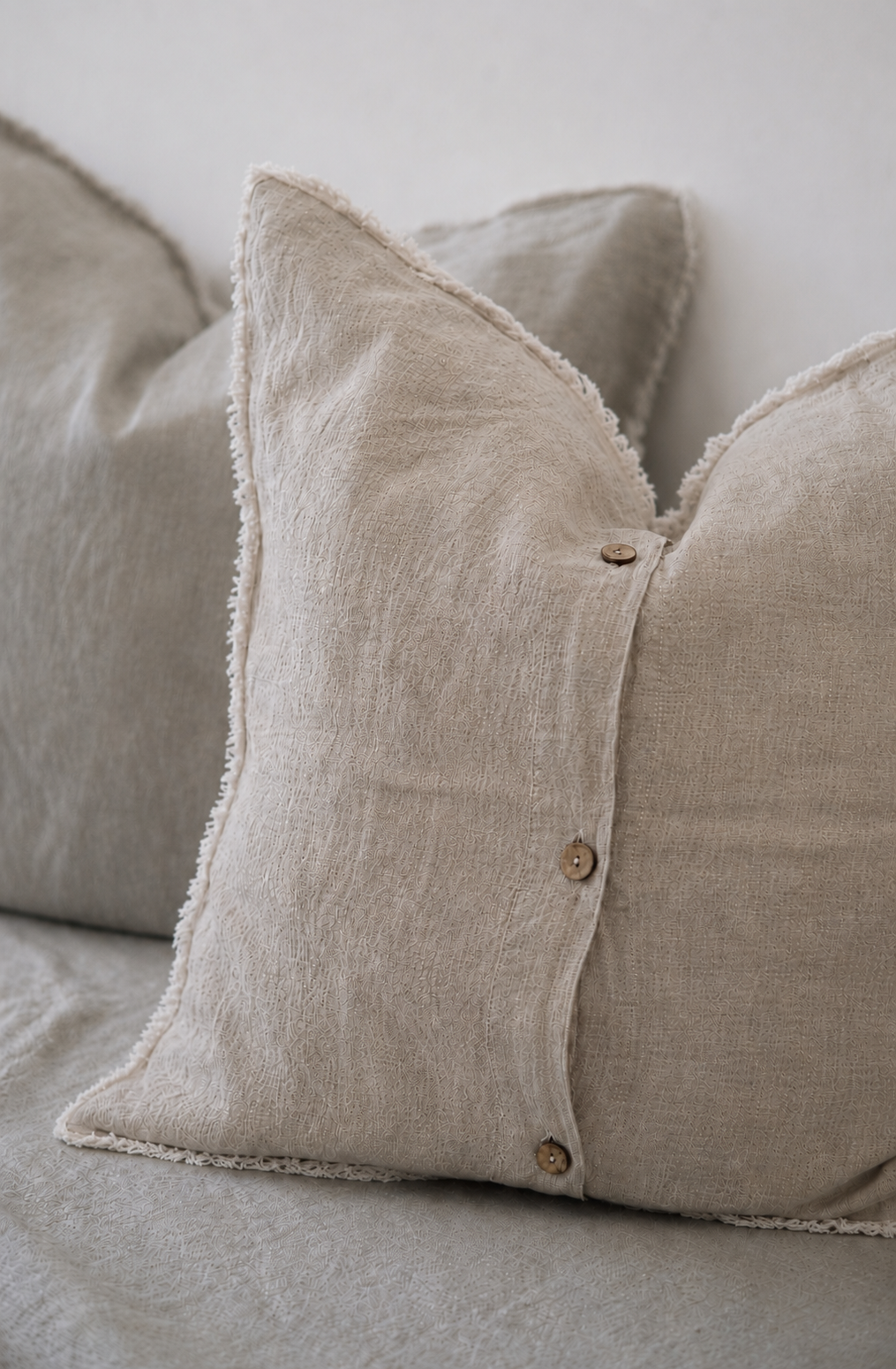 Set of two SOL Linen Sable frayed linen European pillowcases for bedding, shown in a cozy bedroom setting.