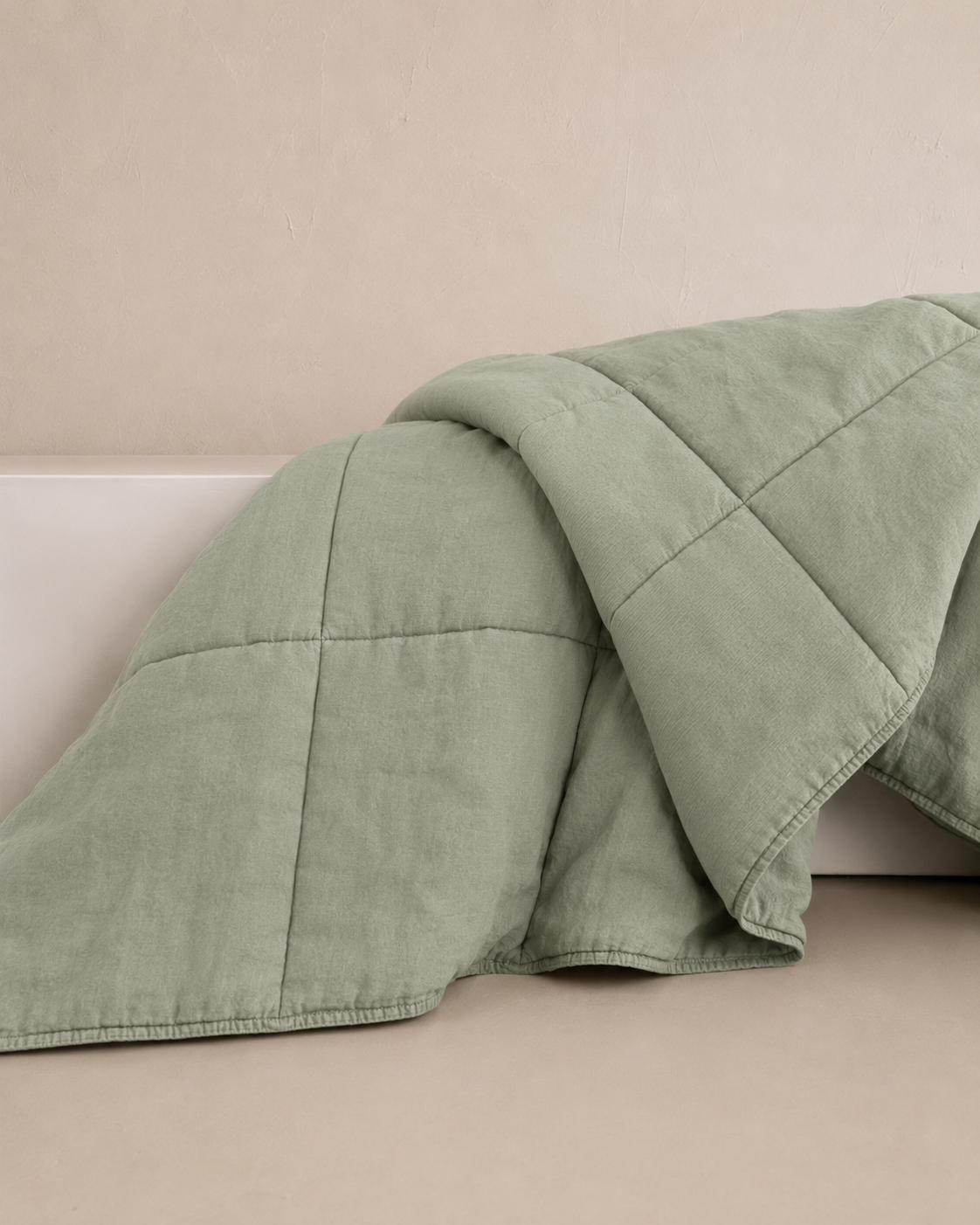 SOL Linen Sea Mist quilted coverlet draped over a bed with natural lighting, showcasing soft linen texture and subtle sea mist color.