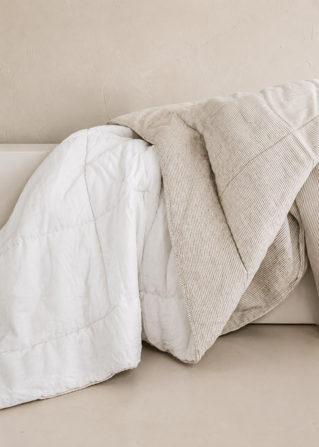 SOL Linen white and ink pinstripe quilted linen coverlet displayed on a bed, showcasing elegant bedding design and texture.