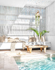 Bright and airy poolside lounge featuring a white built-in sofa with neutral cushions, a rustic wooden coffee table, and a tropical plant in a ceramic vase. Eucalpytus pergola and natural textures create a relaxed, coastal atmosphere