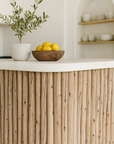 Sanded latte pole kitchen bench styled with a timber bowl of lemons and an olive plant in an organic coastal kitchen.